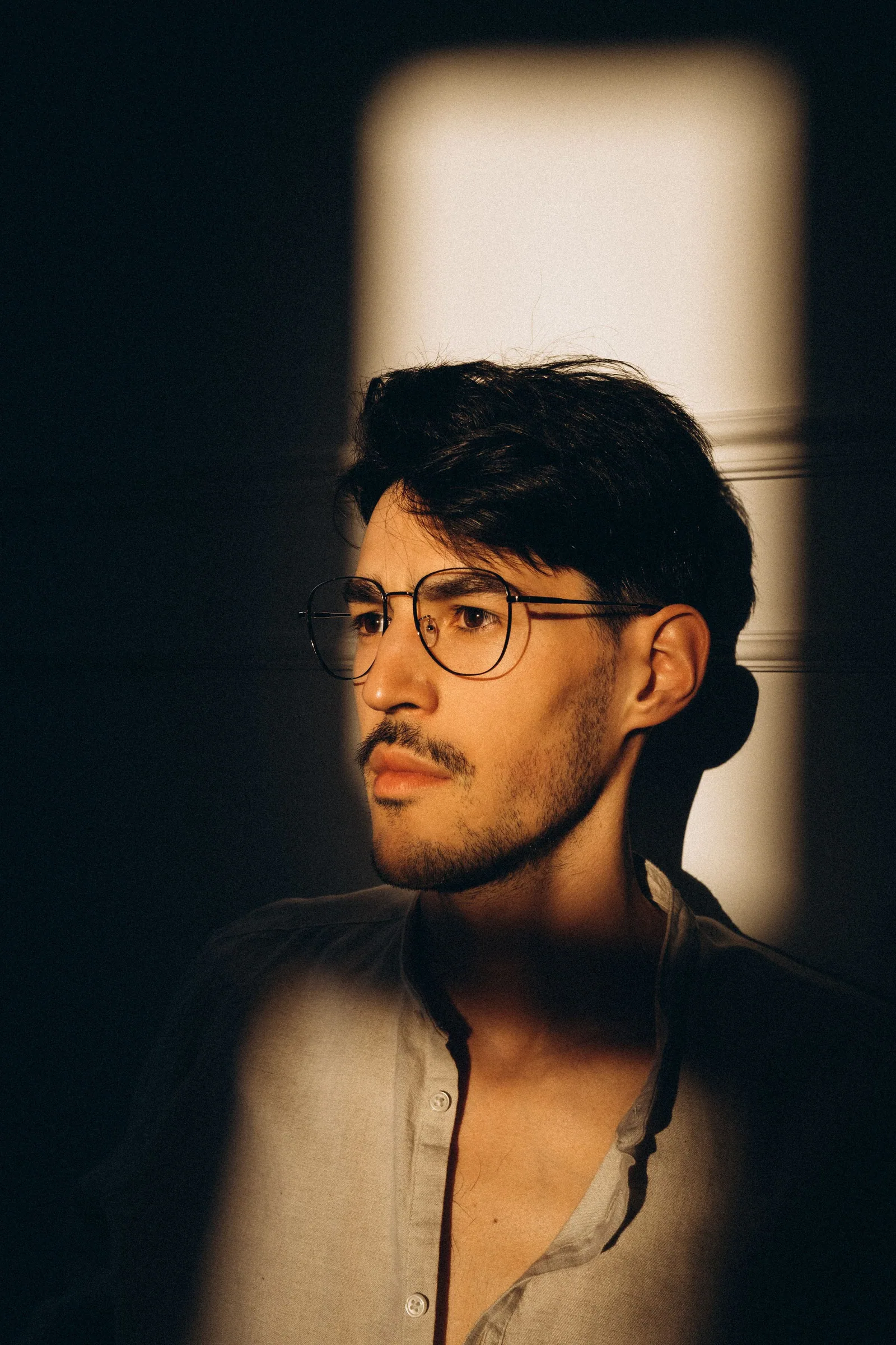 Hombre con gafas bajo la luz de una ventana